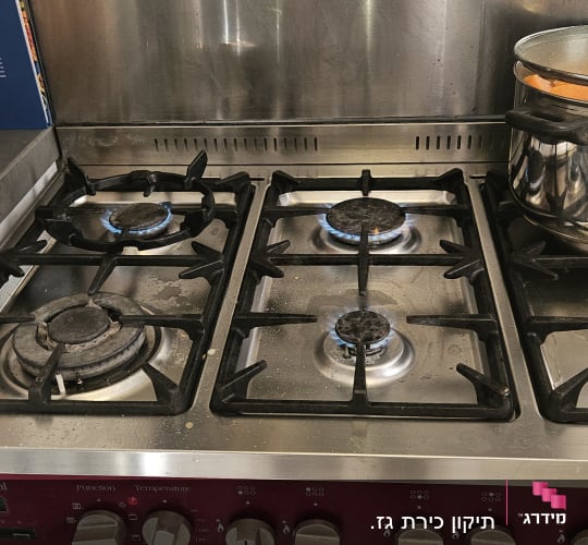 כיריים גז עם סיר נירוסטה על אש דולקת